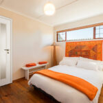 Cozy,Holiday,Bedroom,For,Traveling,Guests,,With,White,Linen,,Orange