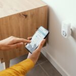 Woman,Setting,A,Smart,Plug,At,Home,Using,Her,Smartphone,